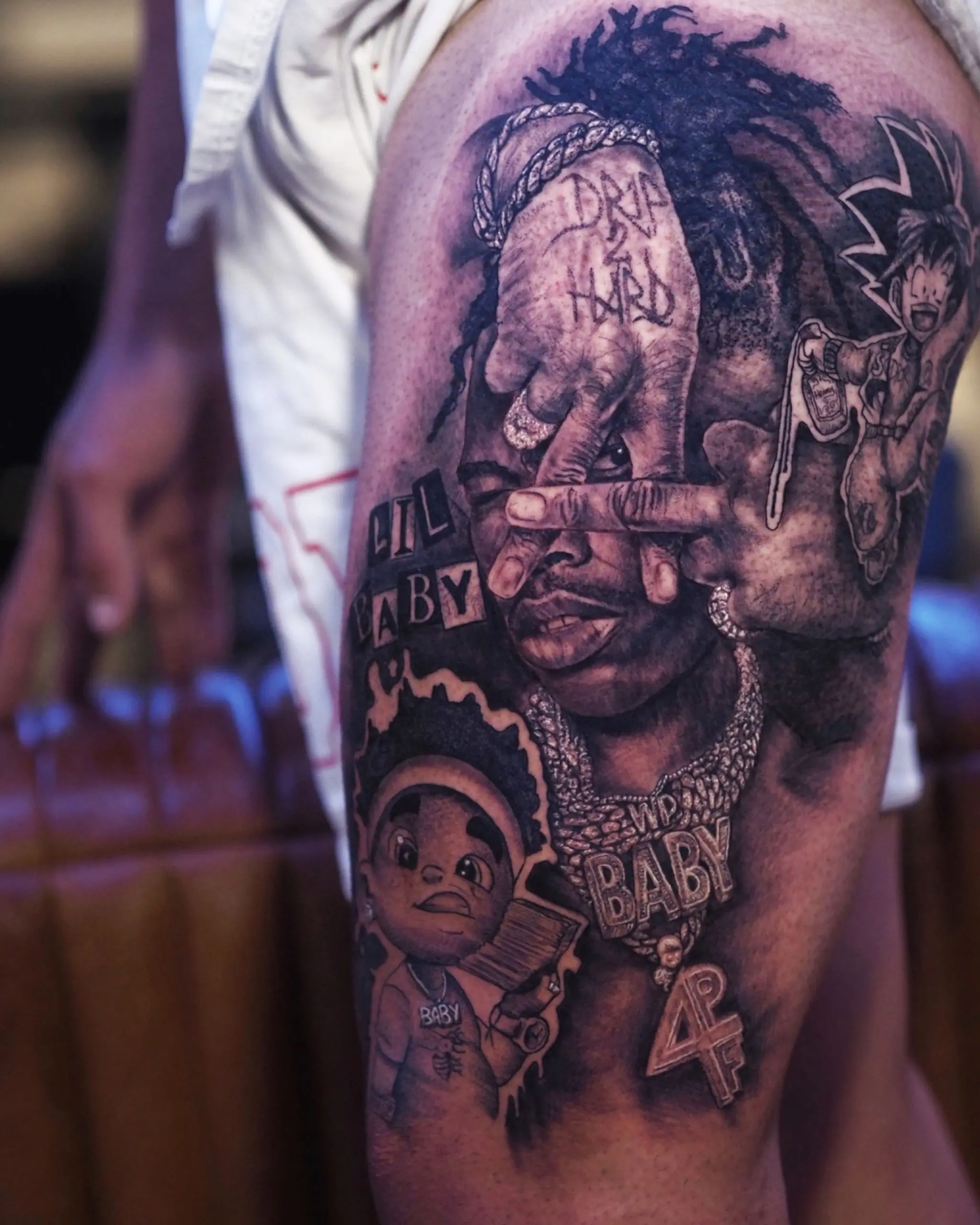 Portrait tattoo of hip-hop artist with Lil Baby text and animated character details by Rahma