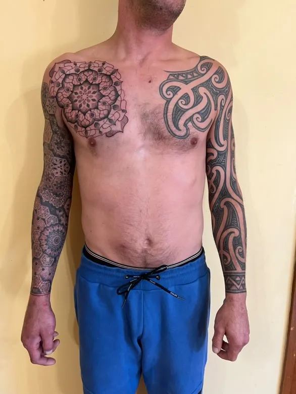 Upper back and shoulder tattoo with spiral design in multiple colors and geometric patterns