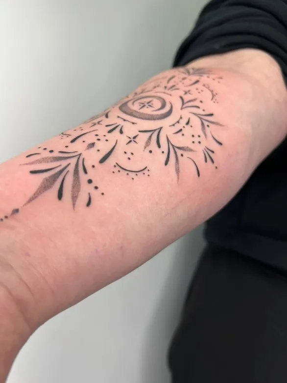 Forearm tattoo with delicate moon phase and botanical elements in fine line style