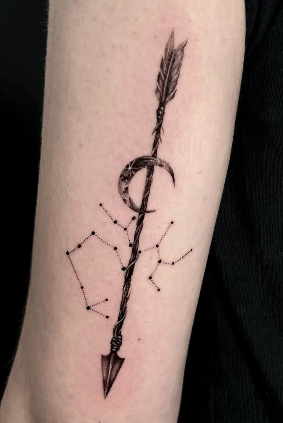 Arrow tattoo with moon and constellation design elements